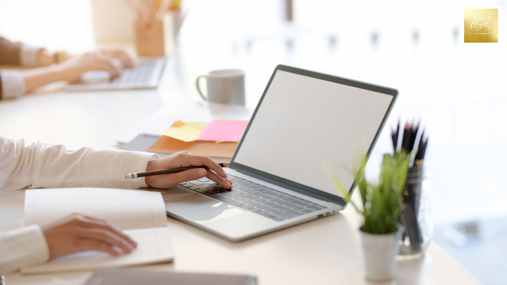 Durch Feng Shui mehr Kreativität im Arbeitszimmer: Hier siehst du die Arme eines Menschen, der an einem Laptop arbeitet, der auf einem ordentlichen Schreibtisch steht.