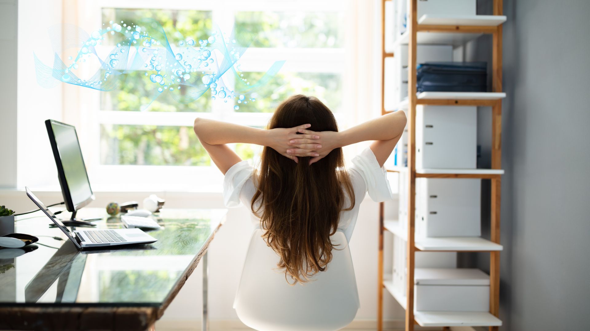 Frau sitzt am Schreibtisch und blickt aus dem Fenster